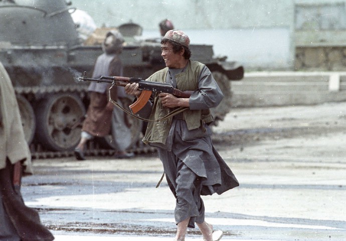 A Dostum mujahideen fighter runs as he fires his AK-47 machine gun